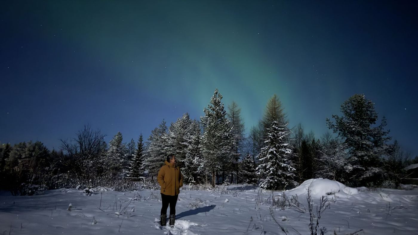 Figura pequena sob a aurora boreal, na Lapônia